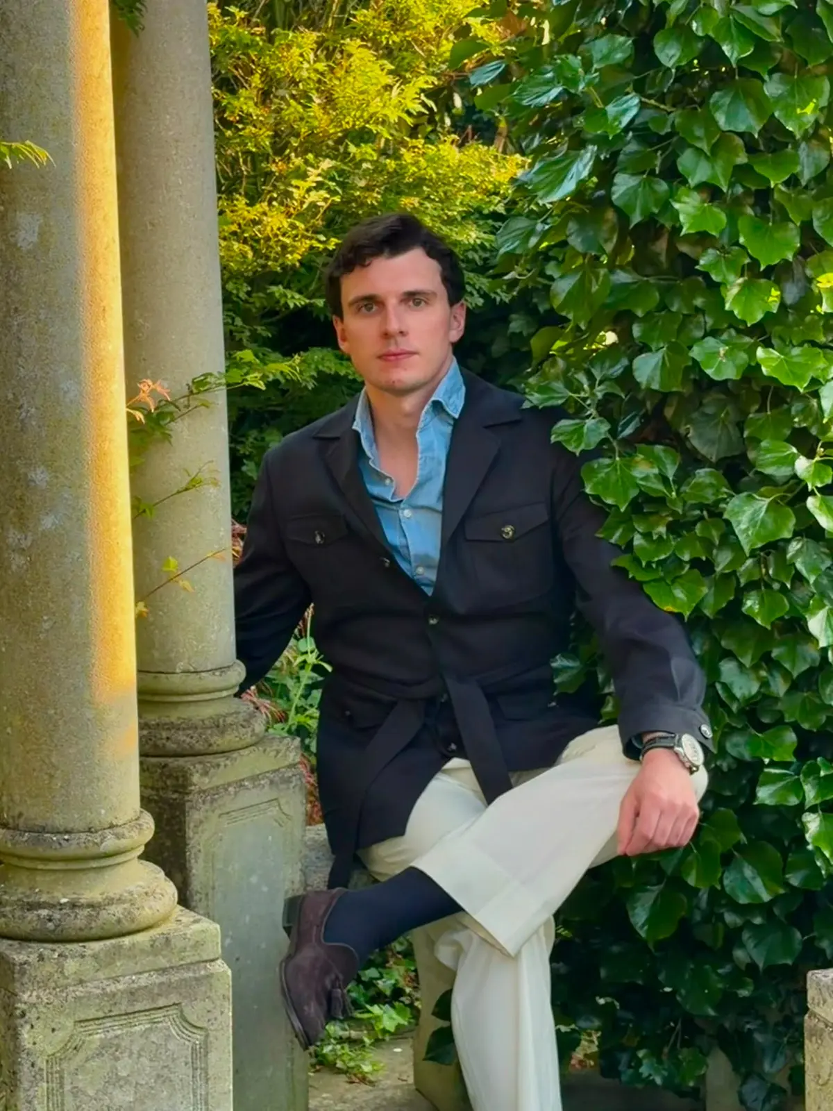 Client seated in a navy safari jacket and cream trousers